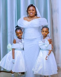The bride and her flower girls in ivory, with bows and pearls to match.